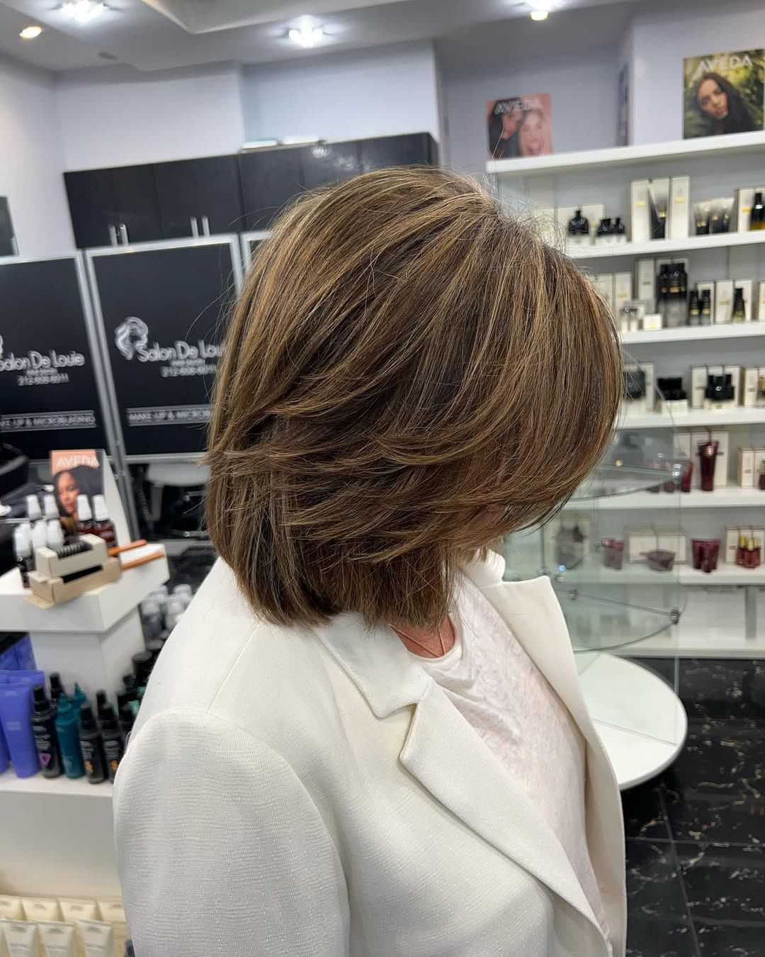 Short-haired person in a salon, showcasing a stylish bob cut with layers and highlights.