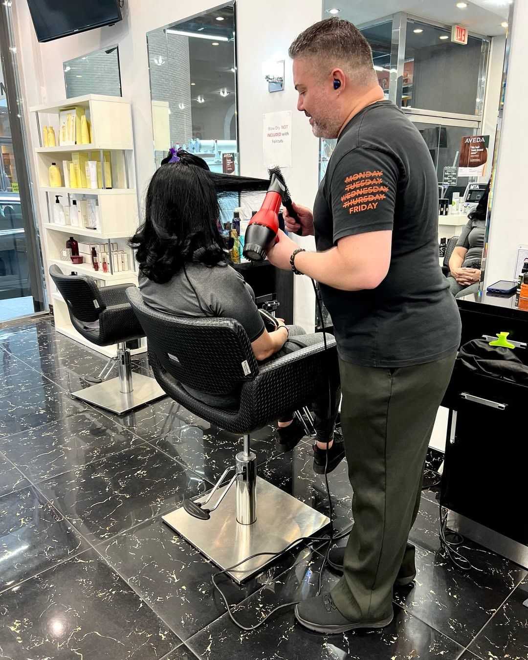 Hairstylist blow-drying a client's hair in a modern salon.