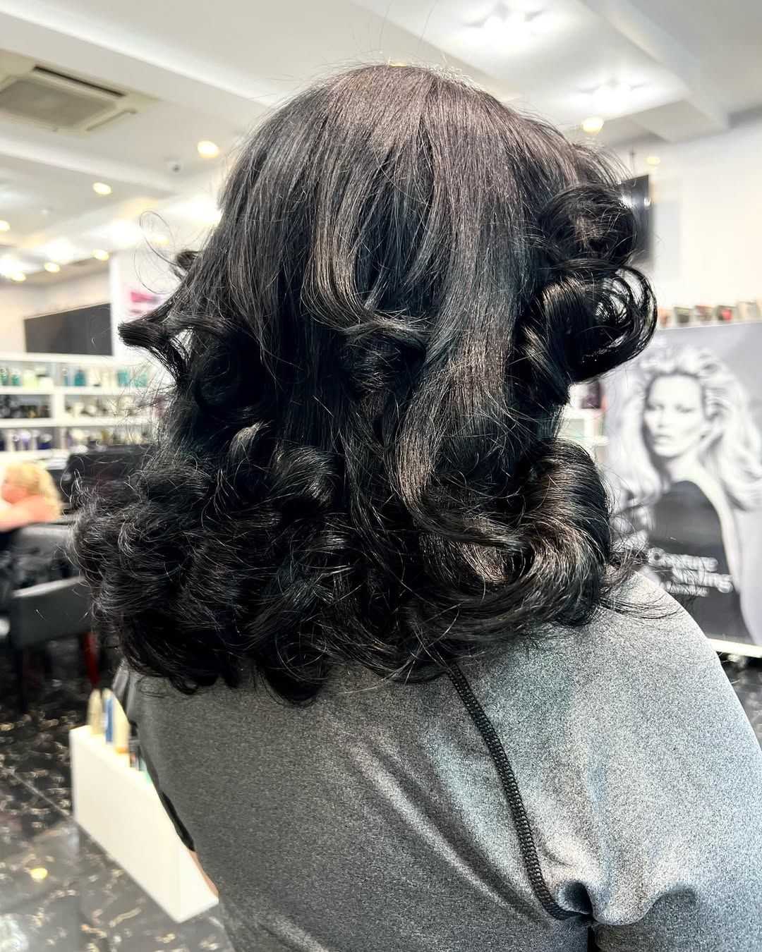 Back view of styled black hair with loose curls in a salon setting.
